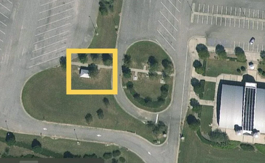 Aerial view of a parking lot and adjacent structures, possibly related to an event area.